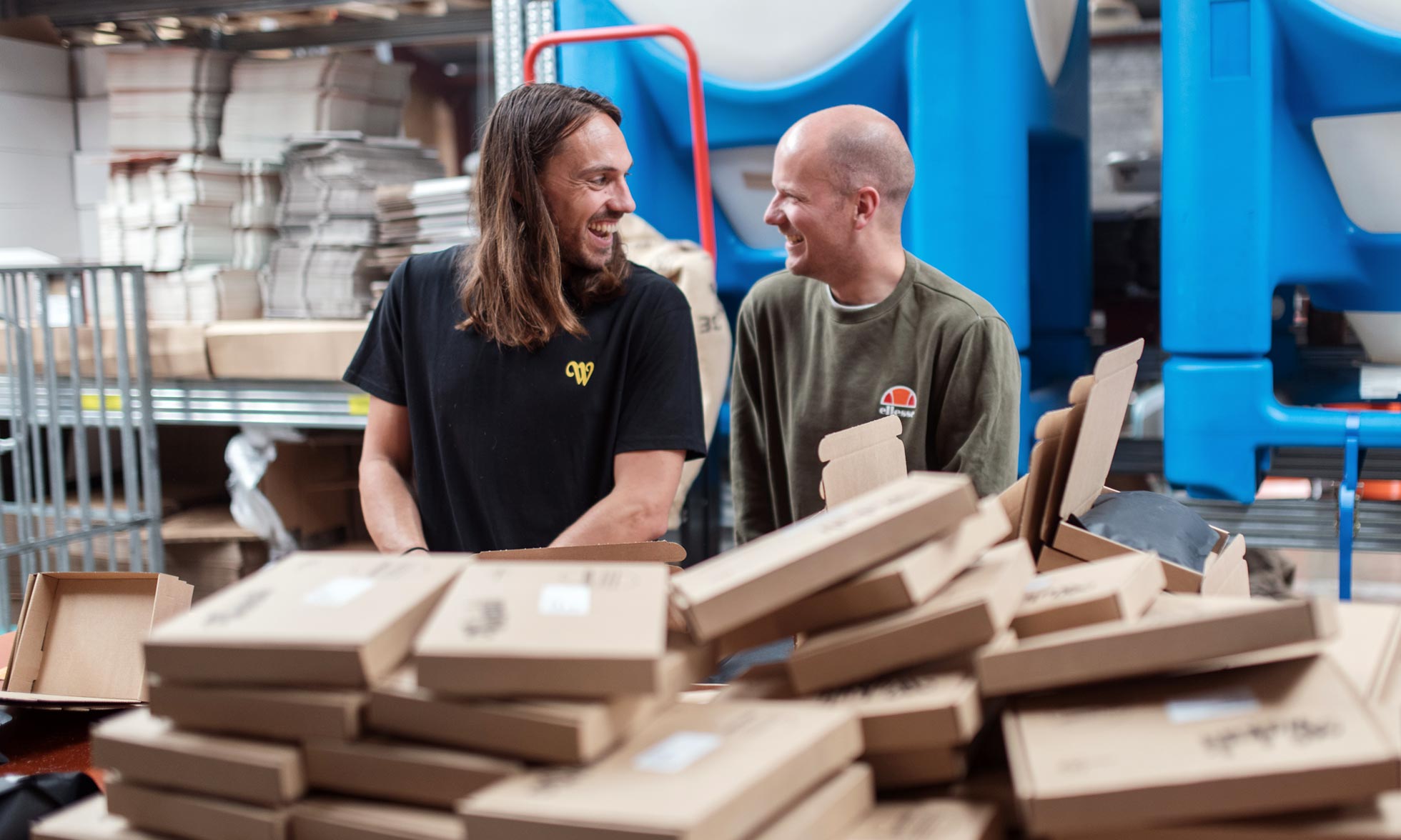 Two smiling guys behind a pile of packages