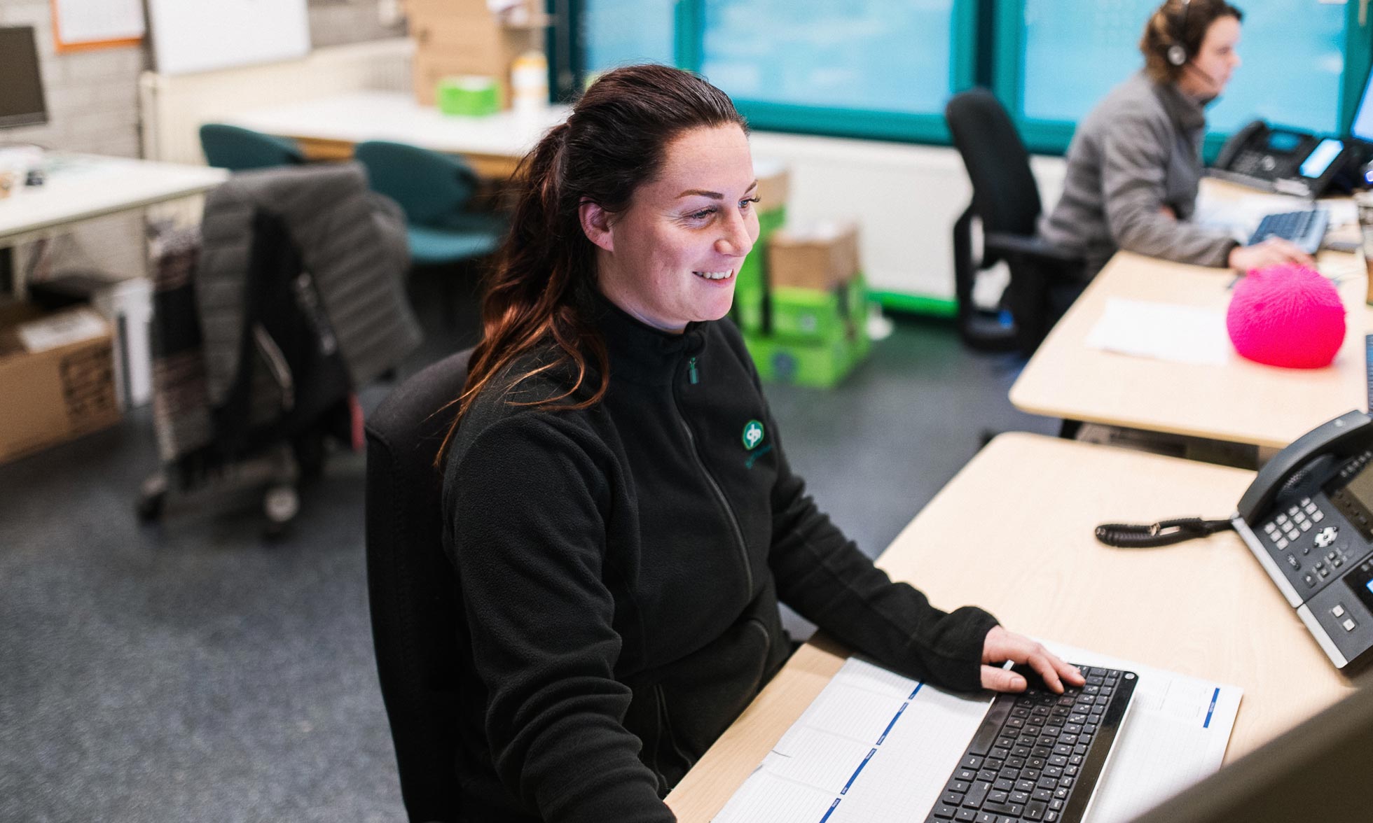 A smiling customer service employee at her desk